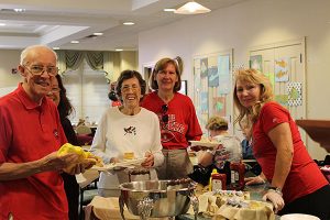 Four people standing around a table with food.